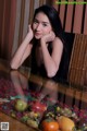 A woman sitting at a table with a basket of fruit.