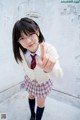 A young woman in a school uniform giving a thumbs up.