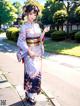 A woman in a kimono standing on a sidewalk.