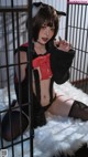 A woman in a black and red outfit sitting in a cage.