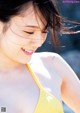 A woman in a yellow bikini smiling at the camera.