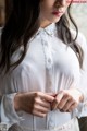 A woman wearing a white blouse and a white lace skirt.