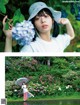 A woman holding an umbrella standing in front of a flower garden.