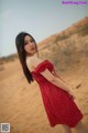 A woman in a red polka dot dress standing in the desert.