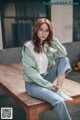 A woman sitting on a wooden bench wearing glasses.