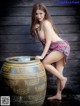 A woman in a bathing suit leaning on a large barrel.