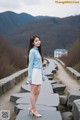 A woman in a blue sweater and white skirt posing for a picture.