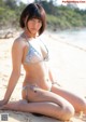 A woman in a bikini sitting on a beach.