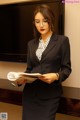 A woman in a business suit is reading a book.