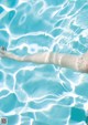 A woman floating in a swimming pool with her arms outstretched.