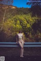 A naked woman standing on the side of a road.