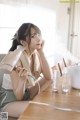 A woman sitting at a table with a hair dryer in her hand.