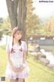 A young woman standing next to a tree in a park.